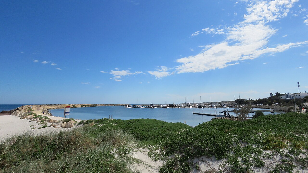 Two Rocks Marina with its limestone rock wall and dune grass under a blue sky.